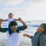 family playing with baby on beach