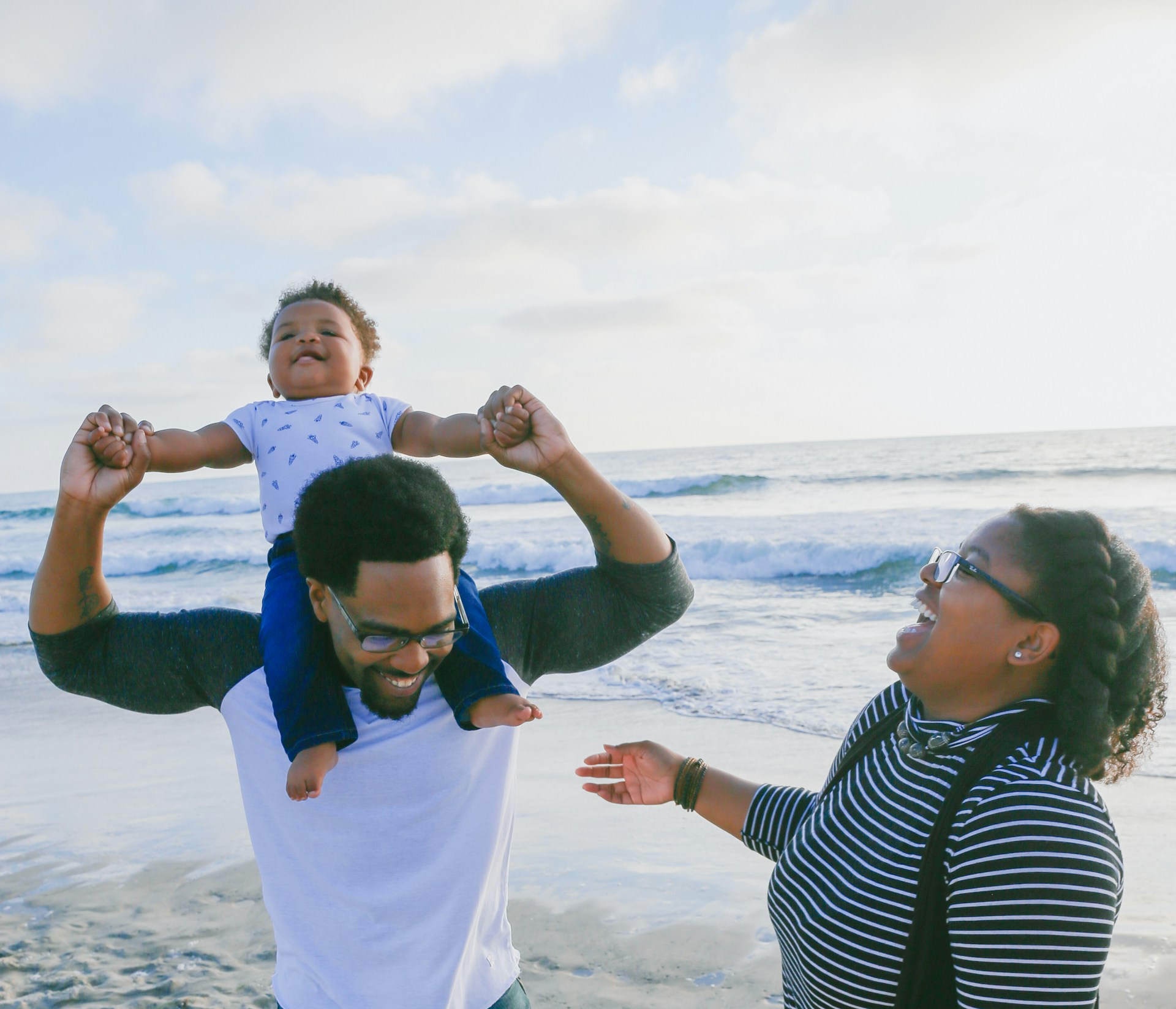 family playing with baby on beach